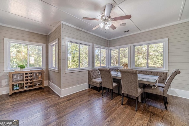 dining space featuring wood walls, ceiling fan, dark hardwood / wood-style floors, and crown molding