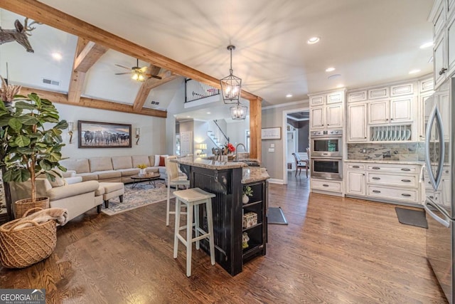 kitchen featuring a kitchen breakfast bar, appliances with stainless steel finishes, hardwood / wood-style flooring, white cabinetry, and light stone counters