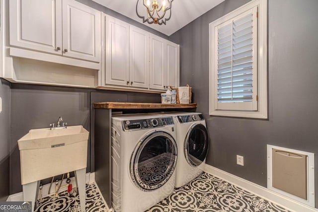 laundry area with sink, cabinets, washing machine and clothes dryer, and a notable chandelier