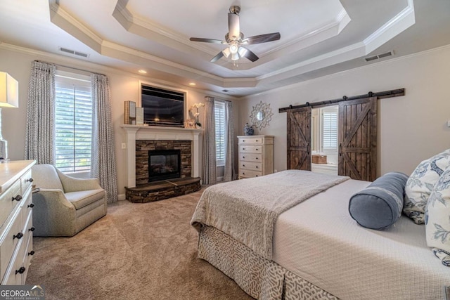 bedroom with ornamental molding, ceiling fan, carpet flooring, a tray ceiling, and a barn door