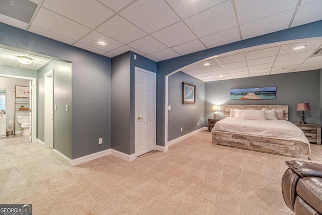 carpeted bedroom featuring ensuite bath, a closet, and a drop ceiling