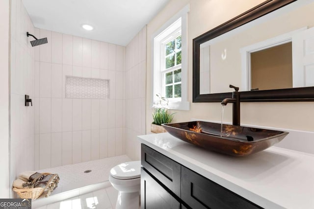 bathroom featuring vanity, toilet, tile patterned floors, and a tile shower