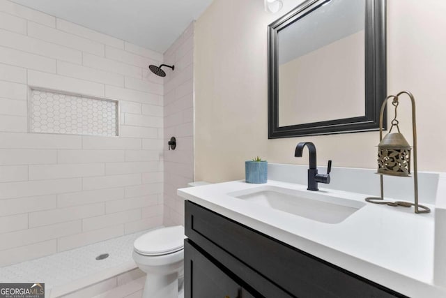 bathroom with vanity, toilet, and a tile shower