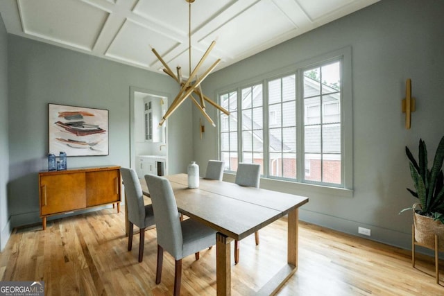 dining space featuring a healthy amount of sunlight, coffered ceiling, and light hardwood / wood-style flooring