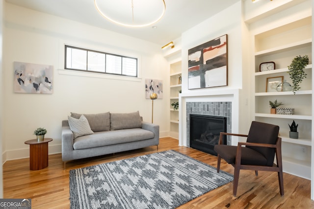 living room featuring a fireplace, built in features, and hardwood / wood-style flooring