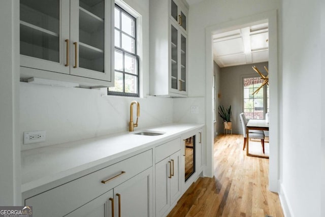 bar with white cabinetry, hardwood / wood-style flooring, and sink