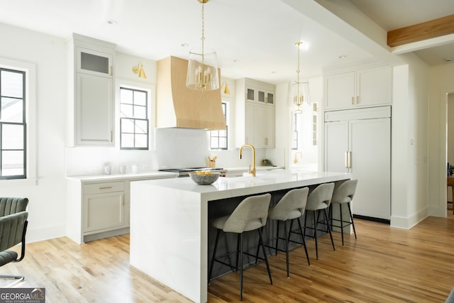 kitchen with a center island with sink, light hardwood / wood-style floors, paneled fridge, and plenty of natural light