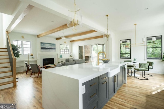 kitchen with an island with sink, a wealth of natural light, decorative light fixtures, and sink