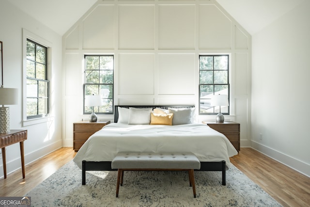 bedroom featuring high vaulted ceiling and light hardwood / wood-style floors