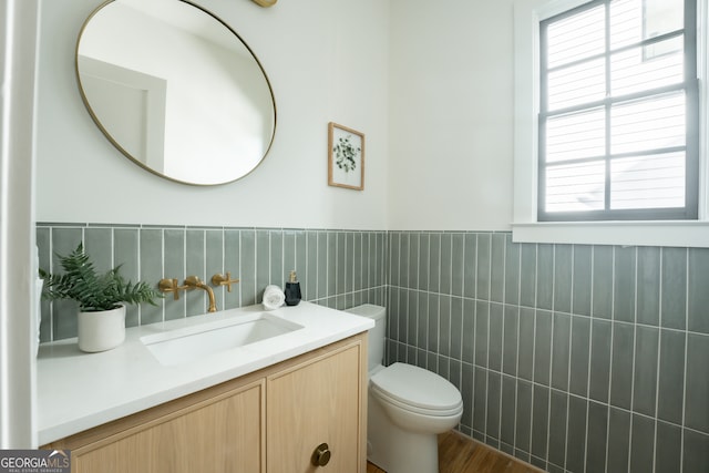bathroom featuring wood-type flooring, vanity, tile walls, and toilet