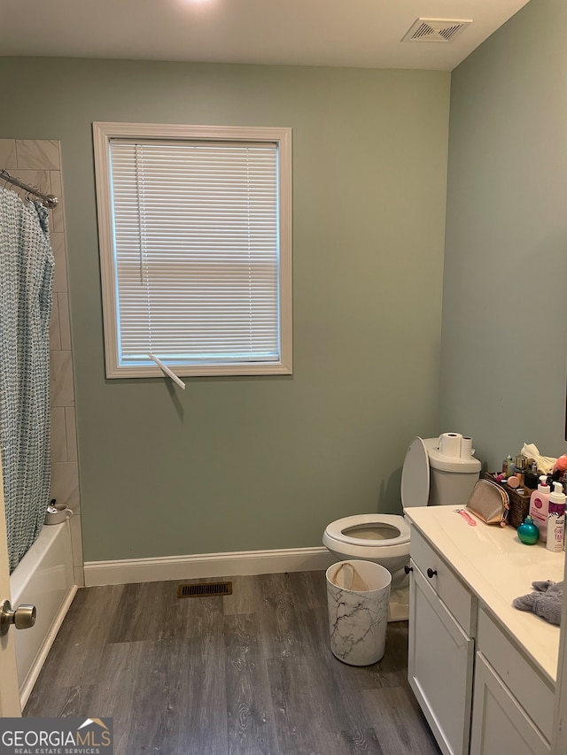 full bathroom with vanity, toilet, wood-type flooring, and shower / tub combo