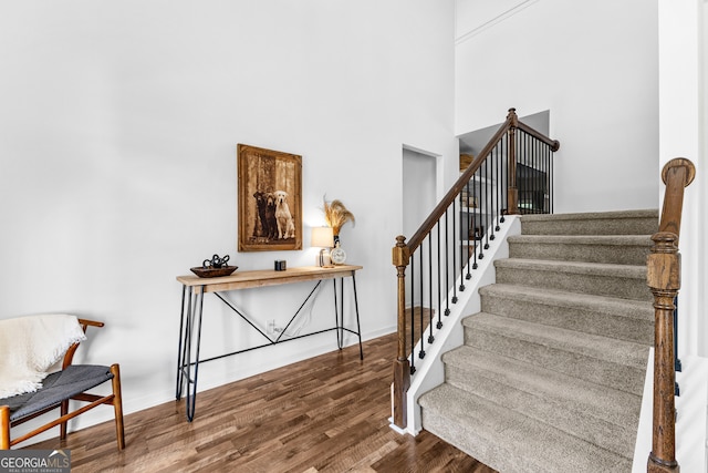 stairs featuring a towering ceiling and hardwood / wood-style flooring