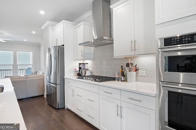 kitchen featuring ceiling fan, white cabinets, wall chimney range hood, stainless steel appliances, and dark hardwood / wood-style flooring