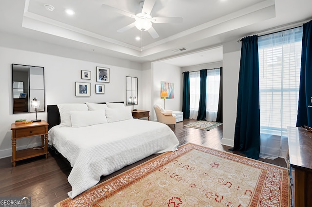 bedroom featuring a tray ceiling, dark hardwood / wood-style flooring, and ceiling fan