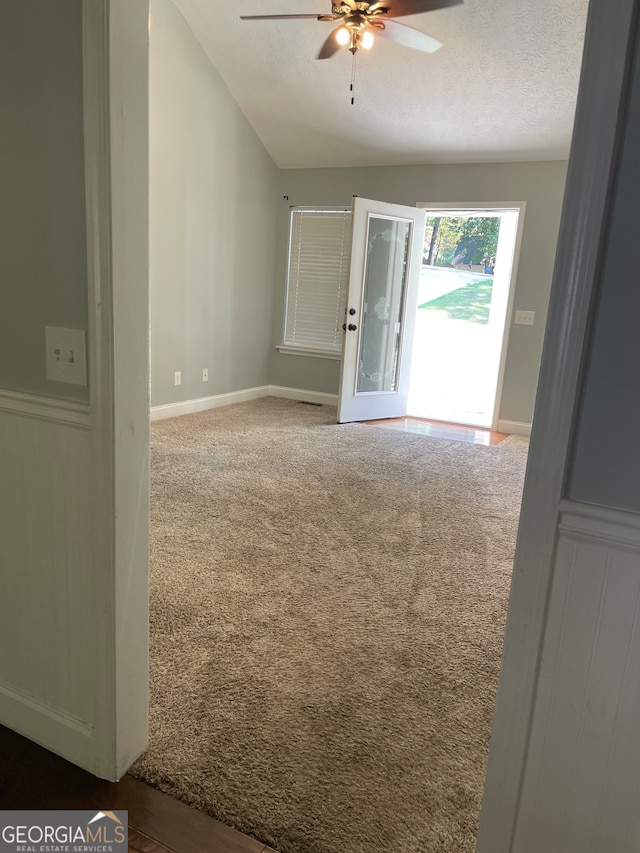 carpeted spare room with ceiling fan, a textured ceiling, and lofted ceiling