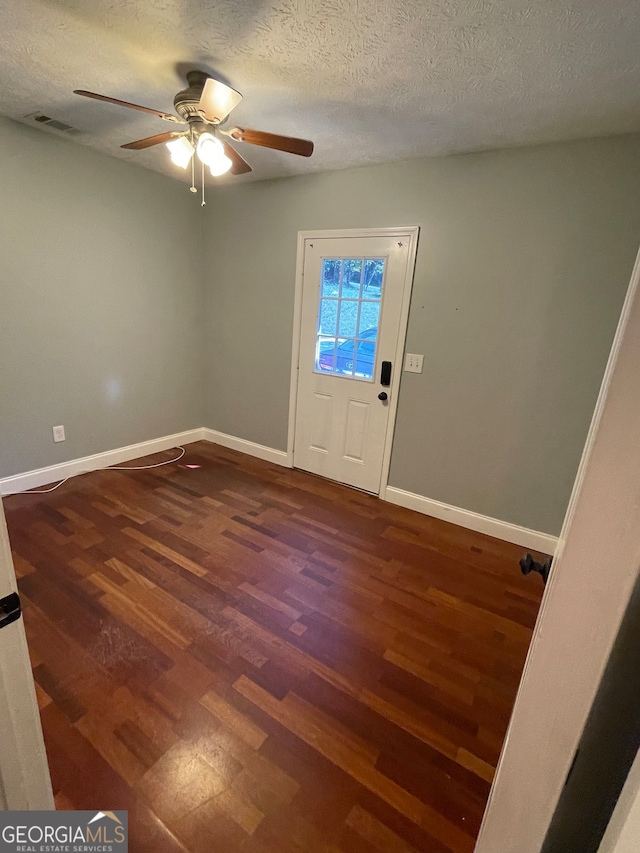 interior space featuring a textured ceiling, dark wood-type flooring, and ceiling fan