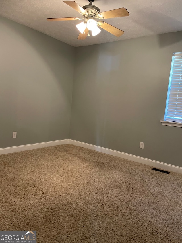 carpeted empty room with ceiling fan and a textured ceiling