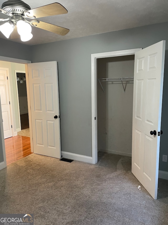 unfurnished bedroom featuring a closet, ceiling fan, carpet floors, and a textured ceiling