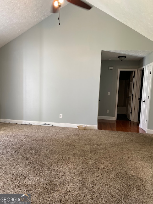 empty room with a textured ceiling, lofted ceiling, dark hardwood / wood-style floors, and ceiling fan