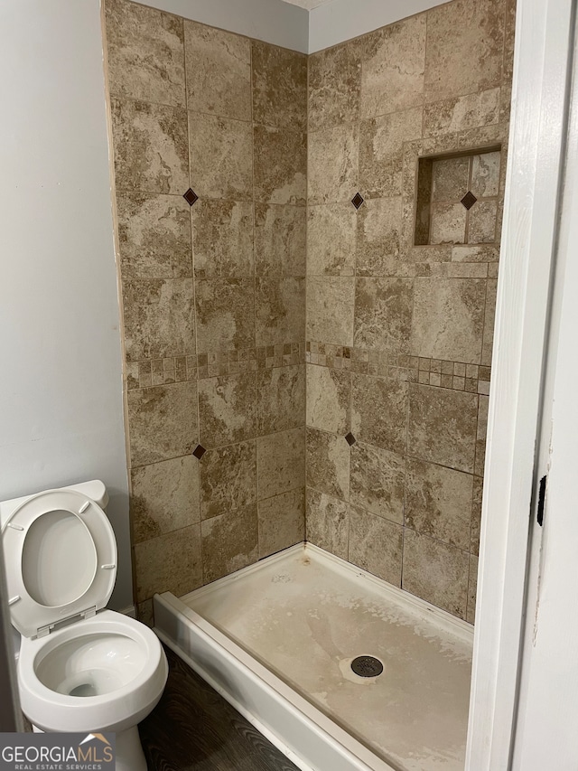 bathroom featuring a tile shower and toilet