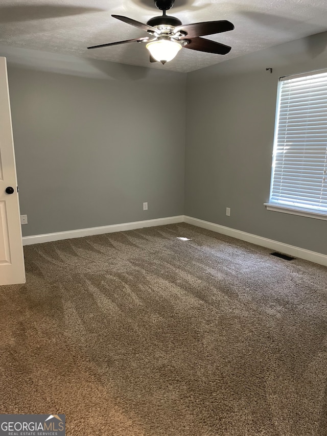 carpeted spare room featuring ceiling fan and a textured ceiling