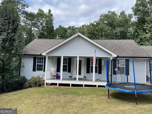 ranch-style home featuring a trampoline, covered porch, and a front yard