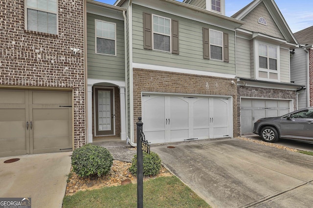 multi unit property featuring brick siding, an attached garage, and driveway