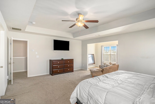 carpeted bedroom with a raised ceiling and ceiling fan