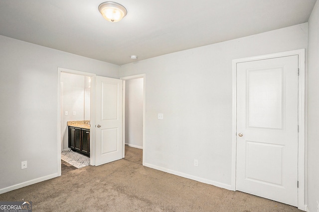 unfurnished bedroom featuring ensuite bath and light colored carpet