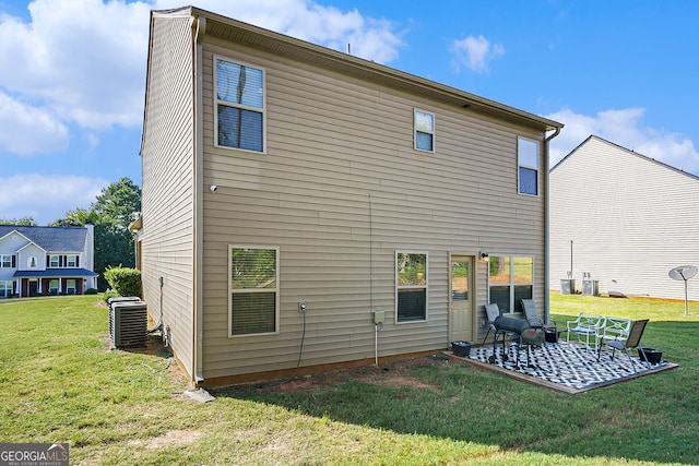 rear view of property with a patio, a yard, and central AC