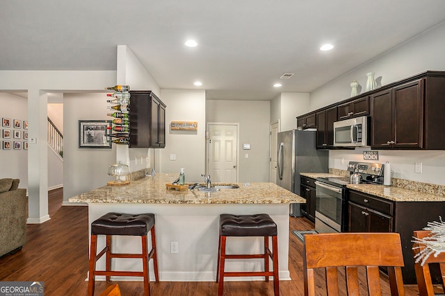 kitchen with a kitchen bar, stainless steel appliances, dark hardwood / wood-style flooring, and kitchen peninsula