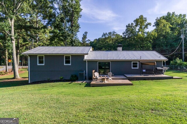 rear view of property featuring a wooden deck, a yard, and cooling unit