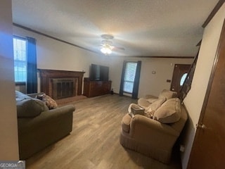 living room with crown molding, ceiling fan, and wood-type flooring