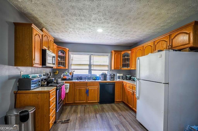 kitchen with appliances with stainless steel finishes, dark hardwood / wood-style floors, a textured ceiling, and sink