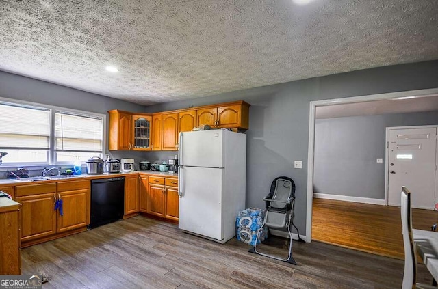 kitchen featuring black dishwasher, a textured ceiling, sink, white refrigerator, and hardwood / wood-style flooring