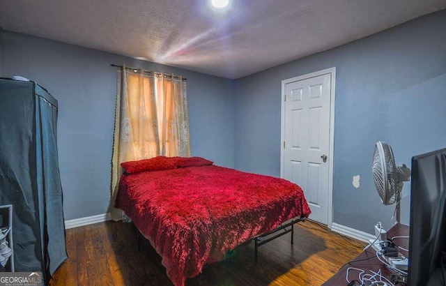 bedroom with a textured ceiling and dark wood-type flooring