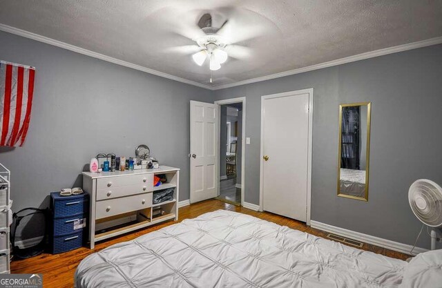 bedroom featuring ceiling fan, a textured ceiling, wood-type flooring, and ornamental molding