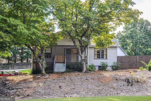 view of property hidden behind natural elements featuring a porch