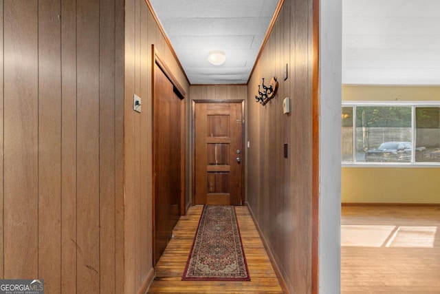 corridor featuring wood walls and light hardwood / wood-style flooring