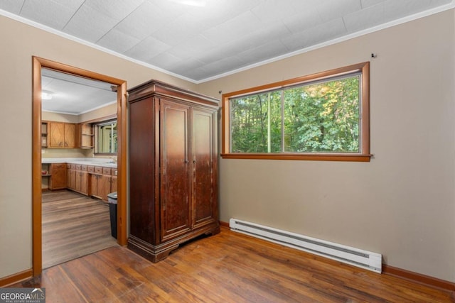 unfurnished bedroom with a baseboard radiator, ornamental molding, and hardwood / wood-style floors