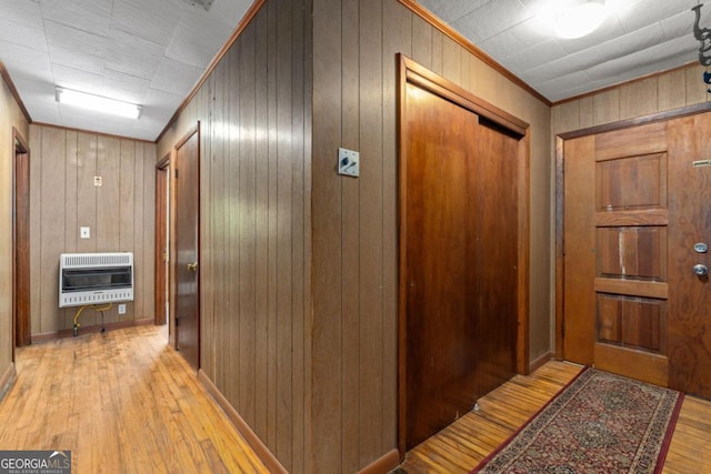 hallway with crown molding, light hardwood / wood-style flooring, heating unit, and wooden walls