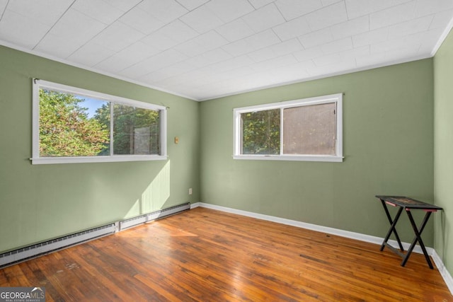 empty room with crown molding, a baseboard radiator, and wood-type flooring