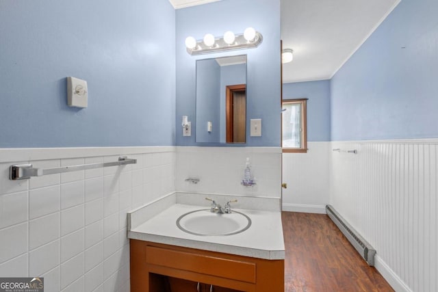 bathroom with vanity, tile walls, hardwood / wood-style flooring, and a baseboard radiator