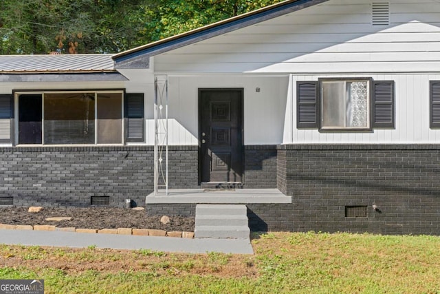 view of exterior entry featuring a lawn