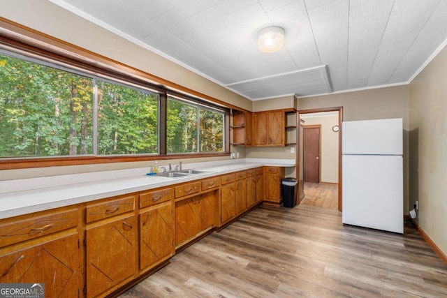 kitchen featuring ornamental molding, white refrigerator, sink, and light hardwood / wood-style floors