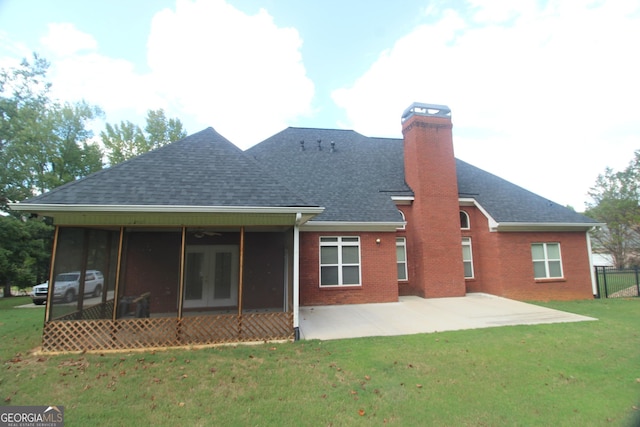 rear view of property with a sunroom, a patio area, and a lawn