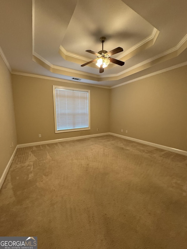 carpeted spare room with crown molding and a tray ceiling