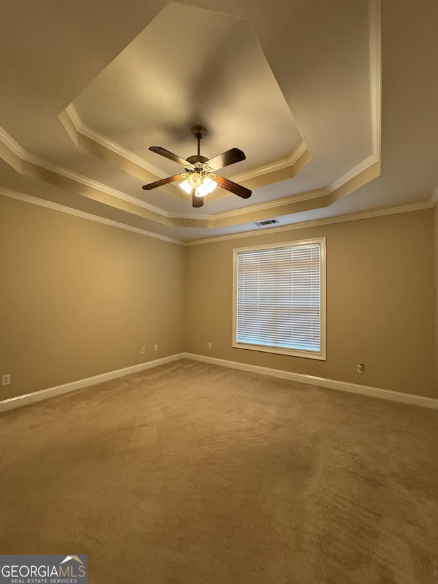 carpeted spare room featuring a tray ceiling, ceiling fan, and ornamental molding