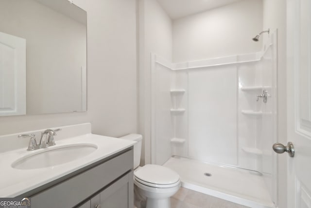 bathroom with vanity, walk in shower, toilet, and tile patterned flooring