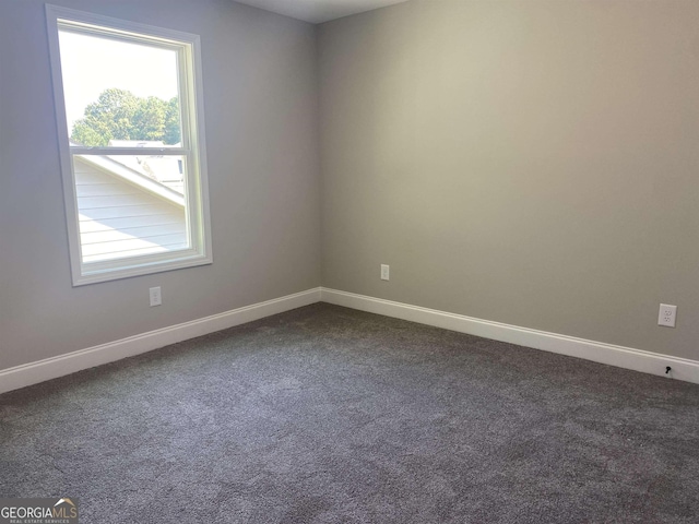 empty room with dark colored carpet and baseboards